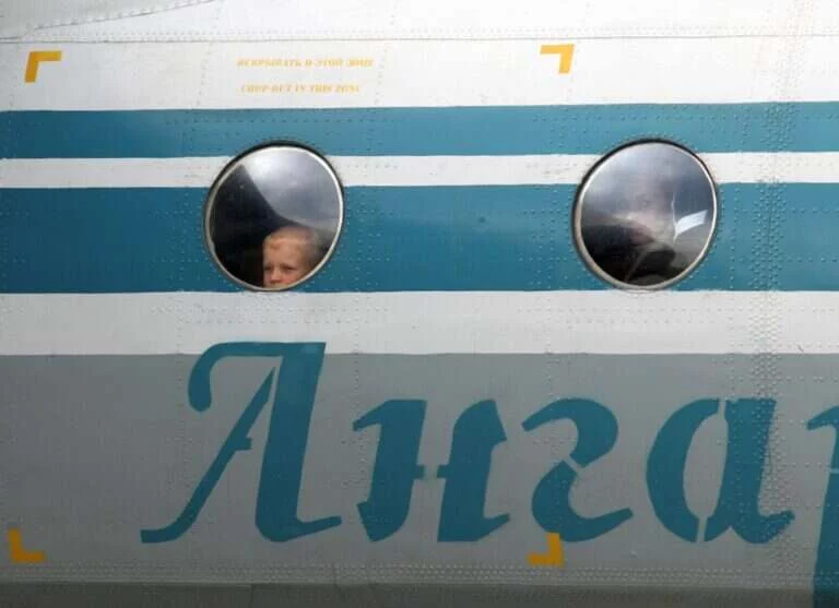 A boy looking out of the cabin window of an aircraft before a flight